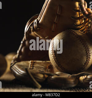 Nahaufnahme Bild eines alten verwendet Baseball und Baseball Handschuh auf hölzernen Tisch in schwarzer Hintergrund Stockfoto