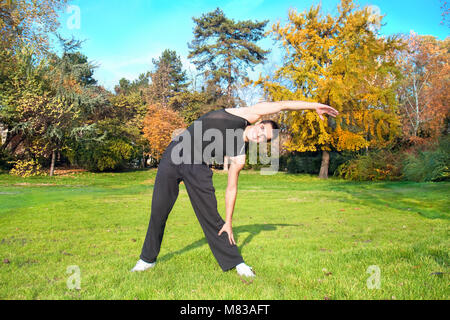 Attraktiven jungen Mann zu tun Übung im Herbst Park Stockfoto