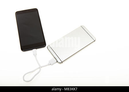 Schwarz Smartphone aufgeladen wird von White Power Bank tragbare Akku durch kurze Ladekabel, von hohen Winkel gesehen Stockfoto