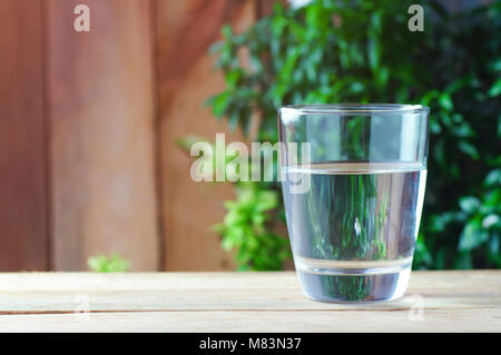 Glas Trinkwasser auf Holz Hintergrund und grüne Natur Stockfoto