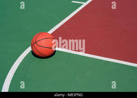 Ein Basketball an der freien Throwlinie auf roten und grünen Hof Stockfoto