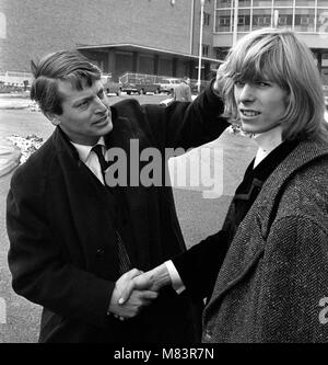Sänger David Bowie, wenn Er wurde bekannt als Davy Jones, dargestellt außerhalb der BBC Television Centre, wo er und seine Band sind mir zu schade der Narr auf der BBC-Show "Gadzooks! Es ist alles da. Die show Produzent Barry Langford bestand darauf, dass Bowie schnitt seine Haare, die er nicht tun und organisierte Demonstrationen bei der BBC mit Bannern wie "Fair Zu lange Haare'. Die Gruppe wurden später auf die Show mit der Bedingung zu erscheinen, wenn sie Beschwerden, das Band der Liebe gehen würde. Es wurden keine Beschwerden erhalten. März 1965 Stockfoto
