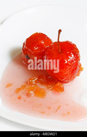 Roter Apfel in rose Sirup mit kleinen Stücken von Zucchini in isolierten weißen Hintergrund Stockfoto