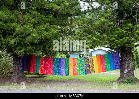 Die Farben des Regenbogens, bunte Material zwischen zwei Bäumen aufhängen in den Cook Island South Pacific zu trocknen. Stockfoto