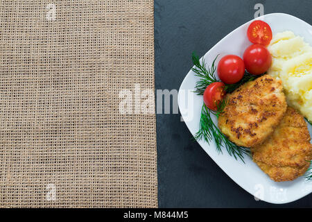 Zwei saftig gebratenes Fleisch Frikadellen auf eine weiße Platte mit Cherry Tomaten und Kartoffelbrei. Stockfoto