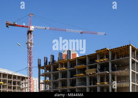 Der Turm Kran baut ein konkretes Haus gegen den blauen Himmel. Stockfoto