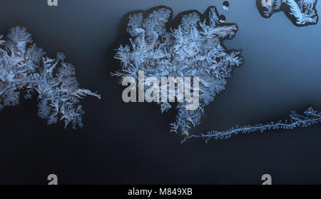 Ornamente auf dem Fenster durch Frost in Blau erstellt. Gefrorenes Wasser auf dem Fenster erstellt odecoration Silber schöne Verzierungen. Stockfoto