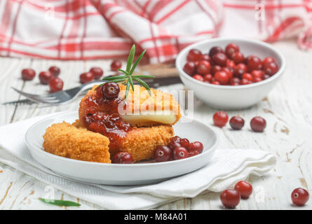 Gebackene Camembert paniert (Brie) mit frischen Beeren und Preiselbeersoße mit Rosmarin auf einem weißen Hintergrund. Gourmet Snack. Frühstück. Selektive Stockfoto