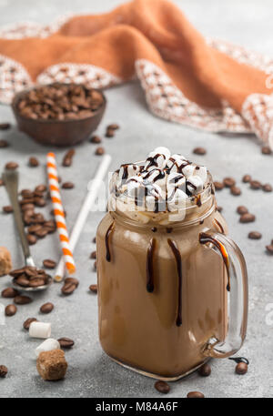 Eiskaffee mit Marshmallows und Schokolade Sirup in einem Marmeladenglas auf grauem Beton Hintergrund. Selektiver Fokus Stockfoto