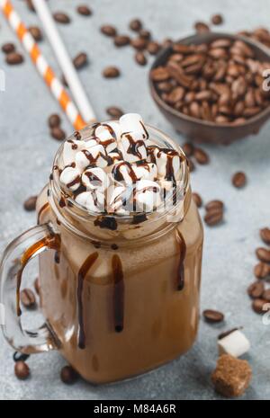 Eiskaffee mit Marshmallows und Schokolade Sirup in einem Marmeladenglas auf grauem Beton Hintergrund. Selektiver Fokus Stockfoto