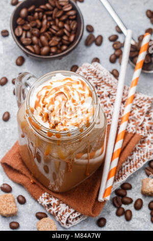 Iced Coffee Latte in einem Marmeladenglas mit Karamell Sirup und Sahne. Selektiver Fokus Stockfoto