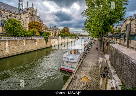 Der Fluss Seine und touristische Boot entlang des Ufers mit der gotischen Kathedrale Notre Dame in Aussicht an einem bewölkten Tag im Frühherbst in Paris Frankreich Stockfoto