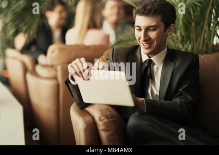 Unternehmer - Anfänger mit einem digitalen Tablet sitzen auf der Couch in der Lobby eines modernen Büro Stockfoto