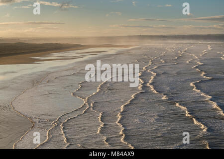 Brechende Wellen rollen Richtung Saunton Sands in der Morgendämmerung in North Devon, England. Im Winter (Januar) 2018. Stockfoto