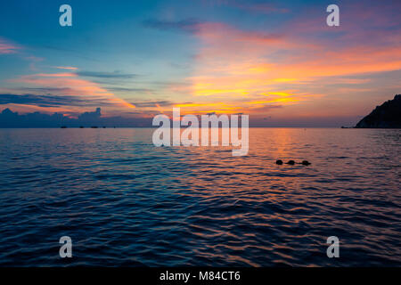 Unglaubliche Sonnenuntergang mit Hälfte blau und gelb, orange und rosa Himmel über dem Meer. Blick auf Koh Nang Yuan von Ko Tao, mit buoyants im Wasser Stockfoto