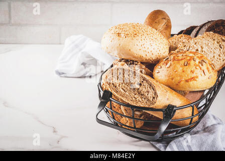 Auswahl an frischen, hausgemachten Korn Brot, in einem Metallkorb, weißem Marmor Background Copy space Stockfoto