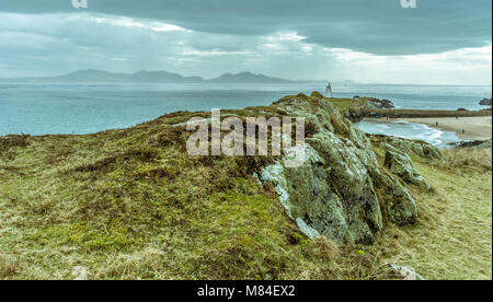 UK, Anglesey, Rhosneigr, 11. März 2018. Ein Blick entlang der felsigen Grat zu Twr Bach Leuchtturm auf llanddwyn Island. Stockfoto
