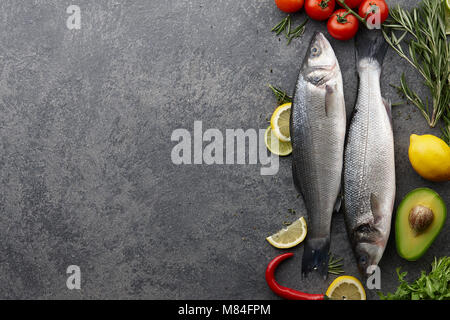 Frische rohe Wolfsbarsch und Zutaten zum Kochen: Rosmarin, Thymian, Limette, Zitrone, etc. Top View copyspace Stockfoto