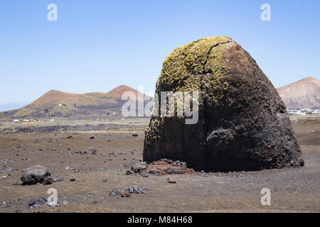 Sehr grosse vulkanische Bombe auf Lanzarote, mit vulkanischen Kegeln im Hintergrund Stockfoto