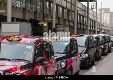 Geparkten schwarzen Londoner Taxis warten auf den Fahrpreis in der Nähe von Kings Cross Station mit dem taxi Licht beleuchtet. Stockfoto