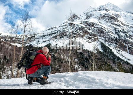 Mann Fotograf ein Bild in die verschneiten Berge nehmen Stockfoto