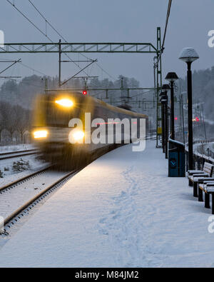 Auch, Schweden - 16. Februar: Moderne Commuter Rail Passenger Zug oder S-Bahn im Schnee im Winter nähert sich Bahnhof Model Release: Nein Property Release: Nein. Stockfoto