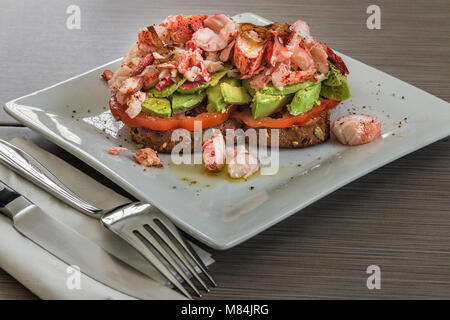 Ein weißer Teller mit ein getoastetes Sandwich mit Tomate, Avocado, übrig gebliebene Karabinerverschluss Fleisch, und knusprig gebratene Schalotten. Stockfoto