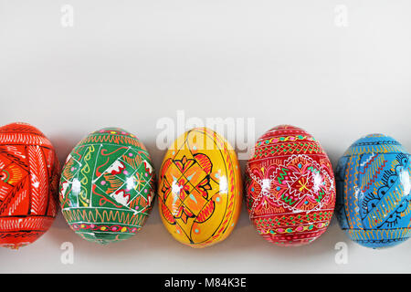 Farbenfrohe handgefertigte Ostereier in der Zeile auf weißem Hintergrund. Traditionelle tschechische Ostern Dekoration. Stockfoto