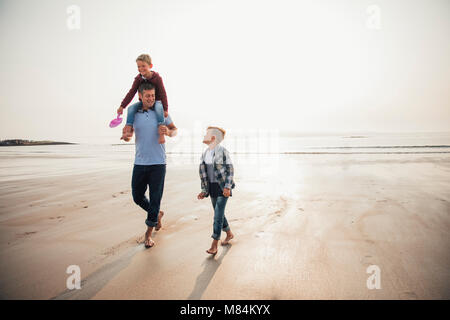 Vater und seine beiden Söhne zu Fuß uyp aus dem Wasser am Strand, während auf Ihren Urlaub. Stockfoto