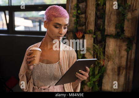 Stilvolle Frau Kaffee, während Sie die digitale Tafel im Restaurant Stockfoto