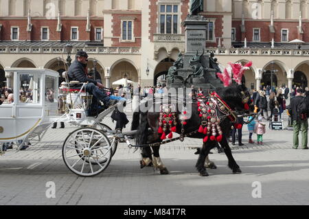 Krakau, Polen - 11. März 2018: Marktplatz, Tuchhallen. Auf der Vorderseite ist eine dekorative Pferdekutsche für den Transport von Touristen. Stockfoto