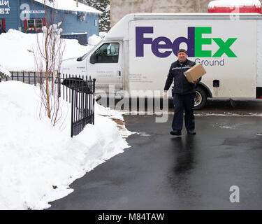 Eine Lieferung von Federal Express liefert ein Paket im Schnee in Spekulant, NY, USA Stockfoto