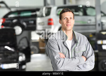 Portrait Mitarbeiter/Mechaniker in der Garage - lächelnder Mann in Arbeitskleidung Stockfoto