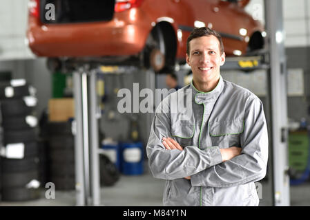 Portrait Mitarbeiter/Mechaniker in der Garage - lächelnder Mann in Arbeitskleidung Stockfoto