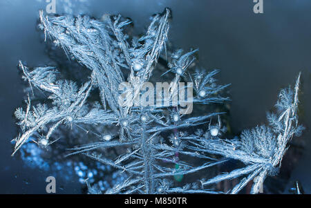 Blauer Hintergrund mit Silver Frost Ornamente auf dem Fenster. Gefrorenes Wasser auf dem Fenster erstellt odecoration Silber schöne Verzierungen. Stockfoto