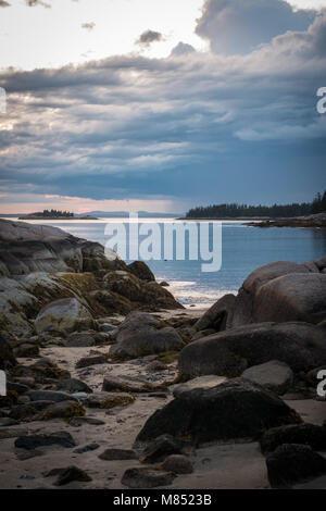 Spektakuläre rosa und orange, stürmische Sonnenuntergang über dem Silber Ozean am Sandstrand in Stonington, Maine. Stockfoto