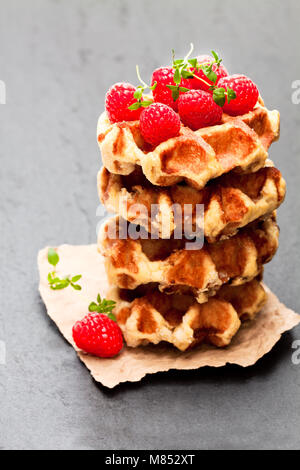 Kontinentale Klassiker belgische Butter Waffeln mit Himbeeren auf schwarzen Stein Hintergrund Stockfoto