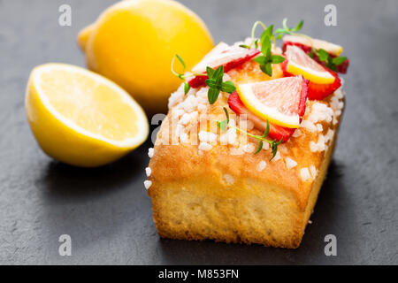 Hausgemachte lemon Loaf mit Erdbeer Slices auf schwarzen Stein Hintergrund Stockfoto