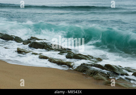 Durban, KwaZulu-Natal, Südafrika, Blur, Nahaufnahme, Wellen brechen auf Reihe von glatten nassen Felsen, Umhlanga Rocks Beach Stockfoto