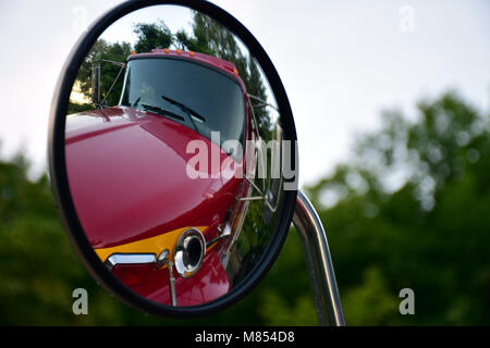 Objekte in den Spiegel kann näher sein, als sie erscheinen. Reflexion eines roten Feuerwehrauto Horn in einer Runde Seite Spiegel. Stockfoto