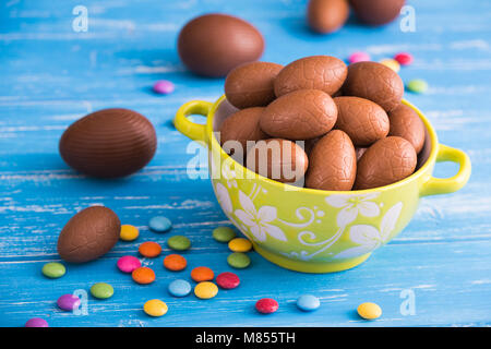 Volle Schüssel von Ostern Schokolade Eier mit Farbe dragiermaschinen u.a. auf einer hölzernen Hintergrund Stockfoto