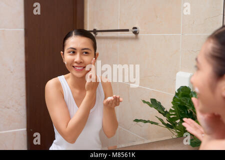 Junge schöne asiatische Frau waschen Ihr Gesicht mit den Händen von Soap Stockfoto