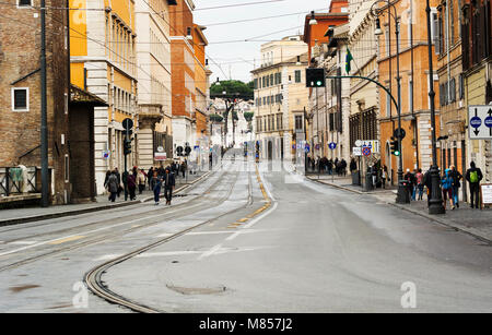 Rom, Italien, März 2015: Blick auf die Via delle Botteghe Oscure in Rom mit den Straßenbahnschienen und Menschen zu Fuß an einem regnerischen Tag Stockfoto