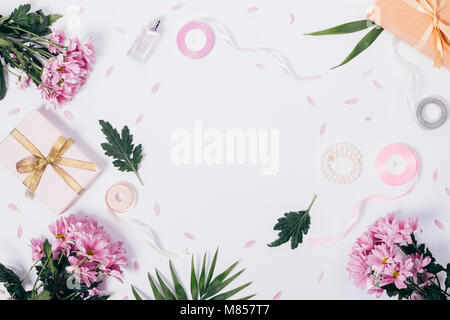 Festliche Zusammensetzung der violetten Blüten, Geschenkboxen und Bändern auf einem weißen Tisch Ansicht von oben Stockfoto