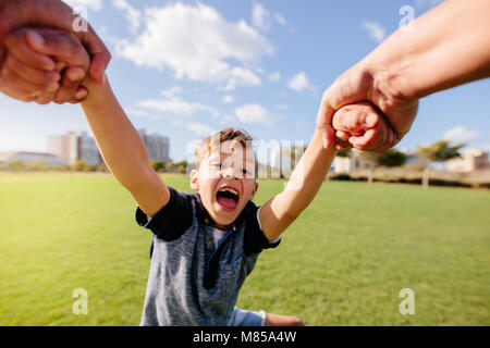 Fröhliche Junge genießt, in die Luft, während das Spielen in einem Park aufgehoben. Nahaufnahme eines Jungen in Spielerische an einem Park. Stockfoto