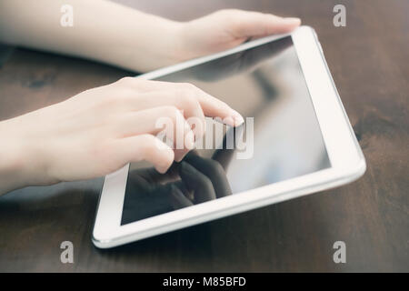Weibliche Halten und berühren Sie eine weiße Tablette auf einem Schreibtisch Stockfoto