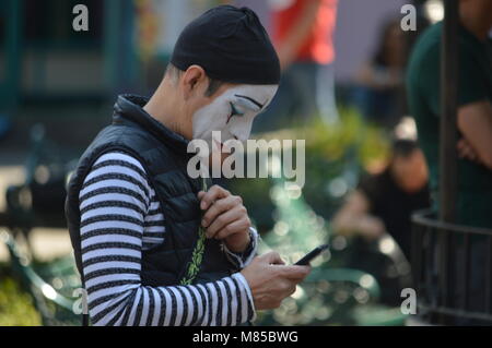 Einen mime-Artist bei seinem Telefon suchen Stockfoto