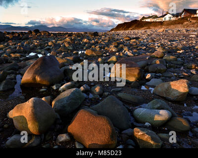 Die felsigen Strand Llandanwg ist warm beleuchtet wie die Sonne über Tremadog Bay entlang der walisischen Küste legt. Stockfoto