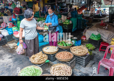 Ein Kunde kauft Gemüse aus einer Frucht Verkäufer an einer im Markt in Hoi An, Vietnam. Stockfoto