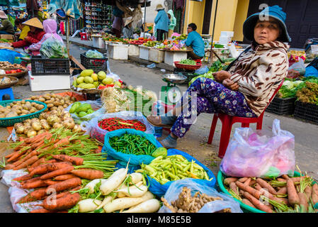 Eine Frau verkauft Gemüse auf der Straße an einer im Markt in Hoi An, Vietnam Stockfoto